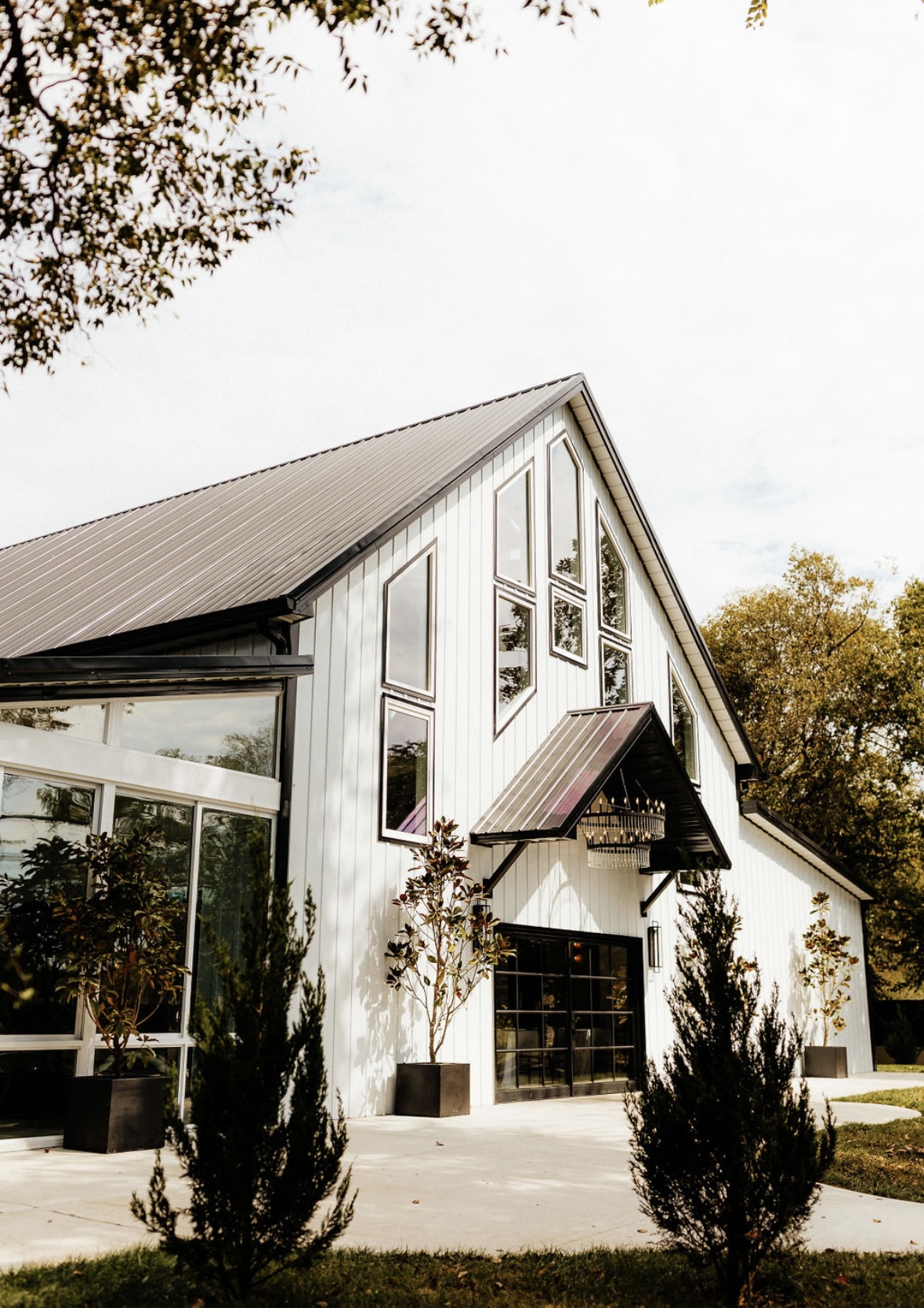An image of a beautiful wedding venue building. The building is white with large, glass windows and stone details.